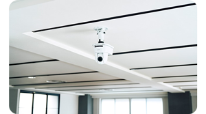 White Sony SRG-A12 PTZ camera mounted to the ceiling of a lecture theatre