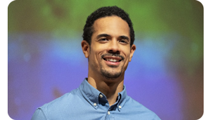 Close up image of male presenter on stage wearing blue shirt