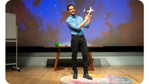 full body image of male presenter on stage wearing blue shirt