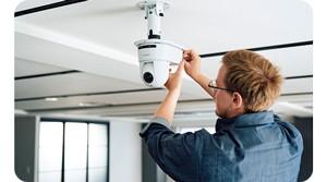 man mounting White Sony SRG-A12 PTZ camera mounted to the ceiling of a lecture theatre