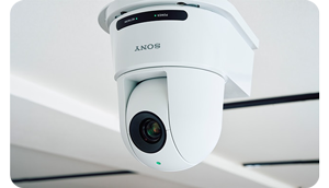 image of white sony SRG-A12 PTZ camera mounted to ceiling with green tally light illuminated