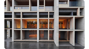 Photograph of a modernist concrete building with warm orange lighting coming from inside
