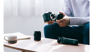 vlogger sat at a coffee table changing lenses on Sony ZV-E10
