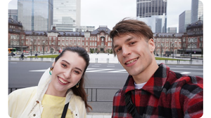 photo of a woman in a yellow top and a man in a red chequered shirt in front of a historical building