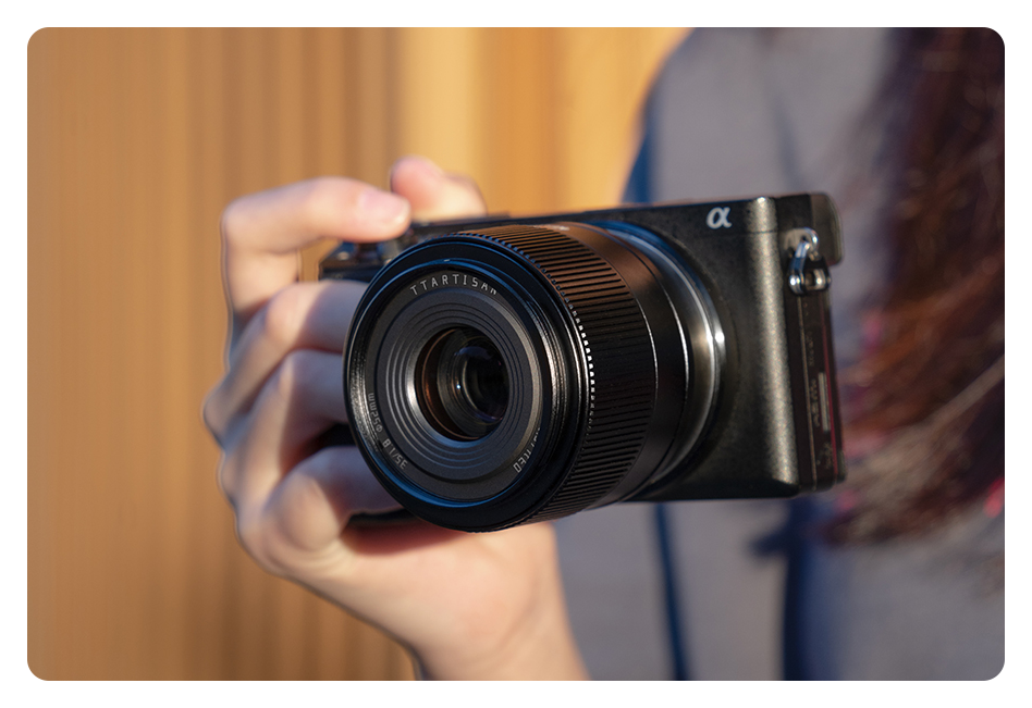somone holding a camera in one hand with the ttartisan af 35mm f1.8 lens attached