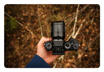 someone holding a camera with the AF 56mm F1.8 APS-C camera lens attacheed