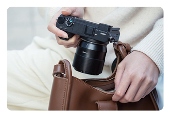 someone taking a camera with the AF 56mm F1.8 APS-C camera lens attached to it out of a bag
