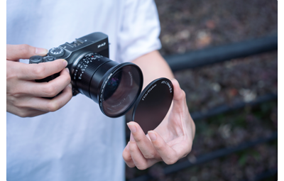 photograph of person holding fujifilm x-a7 with ttartisan 10mm F2 lens and filter adapter and lens cap