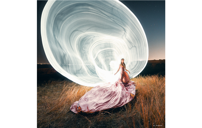 TTArtisan 10mm F2 ASPH sample photograph long exposure portrait of woman wearing long flowing pink dress with light painting circles illuminating the scene