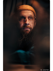 TTArtisan 35mm f0.95 sample photograph of man wearing square framed glasses and orange beanie under warm soft light