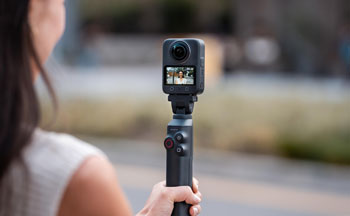 vlogger holding DJI osmo 360 with magnetic charging handle tripod