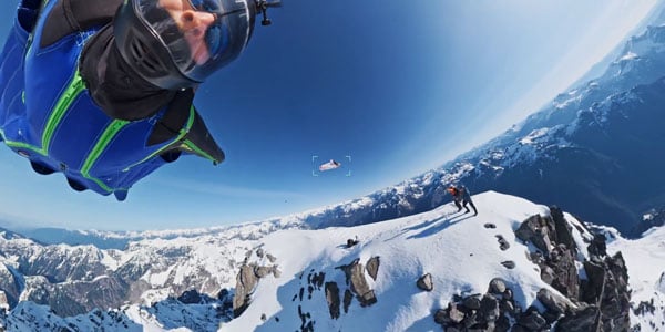 Sky divers flying through sky above snow covered mountains
