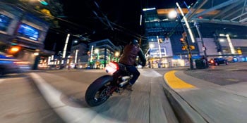 still image of motorcyclist riding through city at night