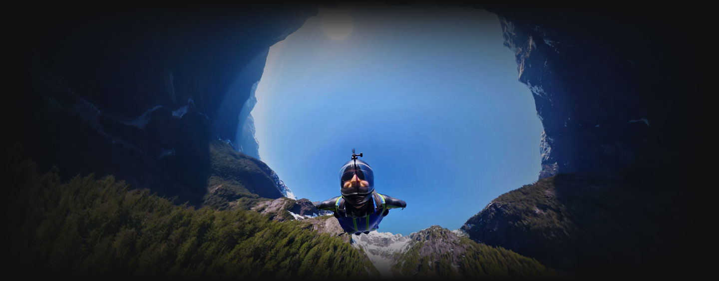 360 image of sky diver flying through mountain forrest area