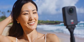 Vlogger holding DJI Osmo 360 while standing on hawaiian beach