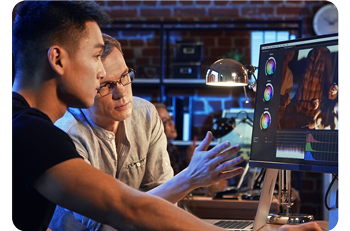 two colourist sat working at desk reviewing a video grade
