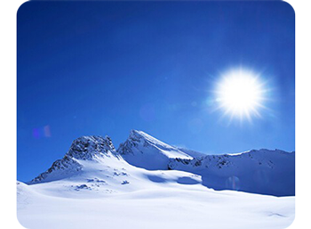 Photograph of snow covered mountains under clear blue sky and bright direct sunlight