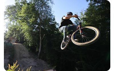 photo of a bmx rider in mid air in a forest taken on the canon r5 camera