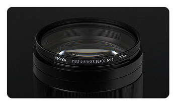 HOYA black mist filter attached to a lens on a black background