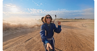 image of race driver standing on dirt track as rally car drives past