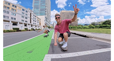 man riding penny board wearing pink t shirt going along american street