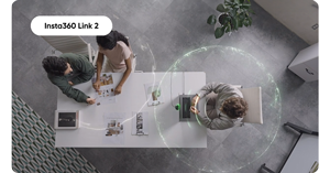 top down image of person working a laptop on desk with two others in conversation