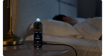 Insta360 X5 standing on bedside table uploading footage to the cloud