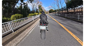 Motorcycle rider driving along road with blurred licence plate