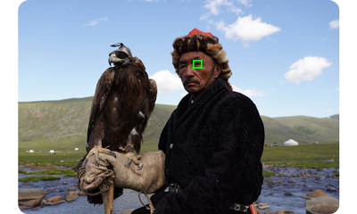 Sony a6600 sample photograph of mongolian eagle hunter holding brown eagle on his glove standing in a mountainous region