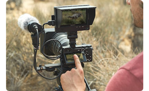 Sony a6600 being used by filmmaker with external atomos monitor and microphone