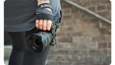 photographer holding sony a6600 camera with E 16-55mm standing infront of bright wall