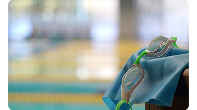 Sony FE 100-400mm G Master Lens sample image of swimming goggles sitting on swimming cap infront of olympic pool