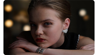 Sony FE 100m F2.8 STF GM OSS Lens sample portrait of woman with her head on her crossed arms leaning on a table wearing expensive jewellery