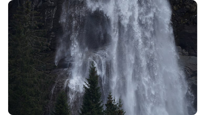 Sony FE 200-600mm F5.6-6.3 G OSS Lens sample photograph of water fall flowing down a mountainside with fern tree forest in the foreground
