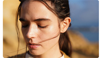 Sony FE 24-70mm F2.8 GM II Lens sample image portrait of brunette haired woman with eyes closed looking downwards light by soft sunlight