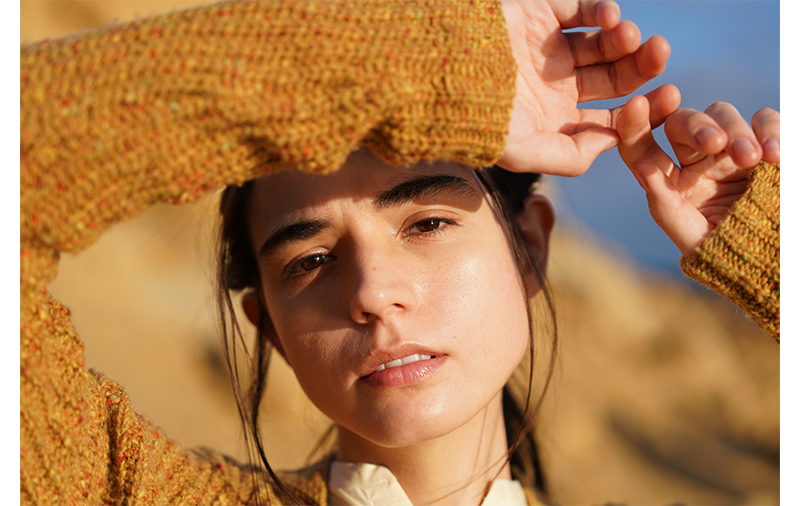 Sony FE 24-70mm F2.8 GM II Lens sample image portrait of brunette woman wearing marled mustard knitted sweater with hands close to her face