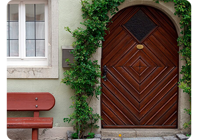 Sony FE 50mm F2.2 Macro Lens sample photograph of patterned wooden archway door surrounded by ivy with a red bench just outside