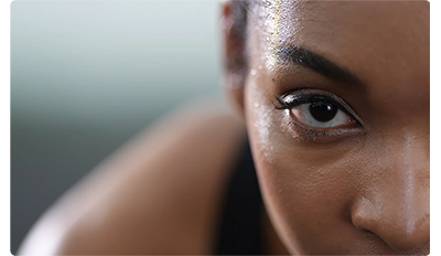 Extreme clos up on a womans dark brown right eye while she uses exercise bike