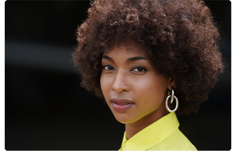 Sony FE 70-200mm F2.8 GM OSS II Lens sample portrait of young black woman with afro hair style chainlink earings wearing a vibrant neon shirt