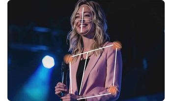 Photograph of Female stage presenter wearing pink blazer speaking on stage with AI Tracking skeleton overlay