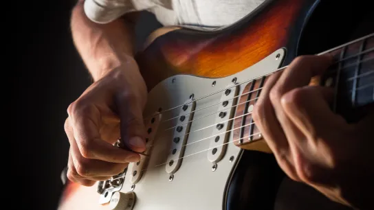 Guitarist trying out an electric guitar in a playing position