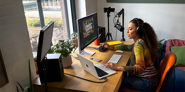 Woman in home studio multi-tasking on her MacBook and Mac.