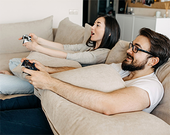couple engaged in competitive gaming on beige couch