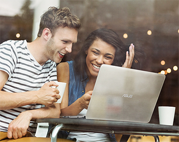 man and lady smiling at laptop outside