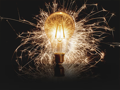 Light bulb with electrical sparks surrounding it.