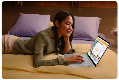 Woman smiling on bed with laptop