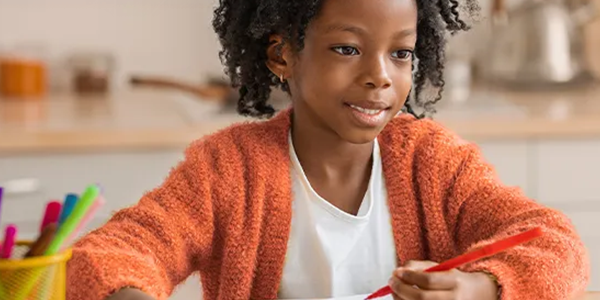 Girl drawing with a red pencil.