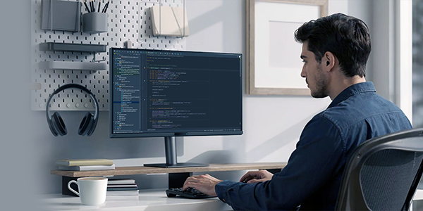 Man sat at desk, working on the BenQ Programming Monitor.
