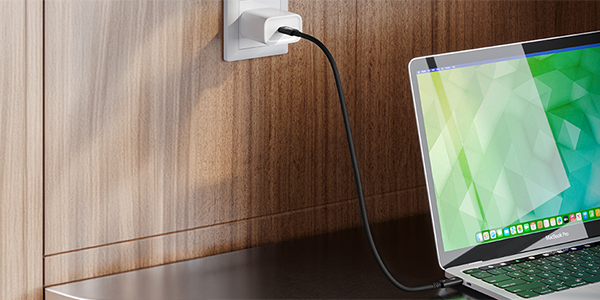 Thunderbolt 5 cable connected from power outlet to a laptop.