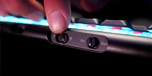 Connectivity switch on the XTRFY keyboard being operated by a thumb